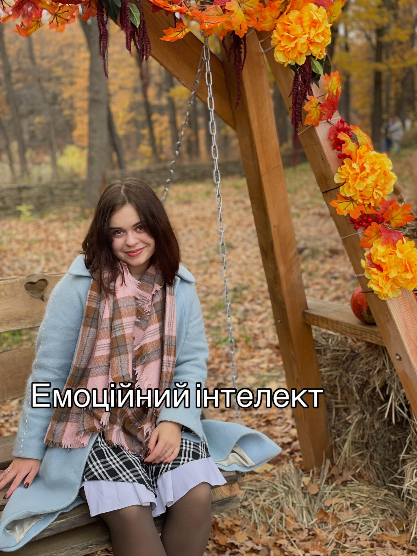 Марія Дерев'янченко сидить на гойдалці серед осіннього декору з помаранчевих квітів; напис «Емоційний інтелект»