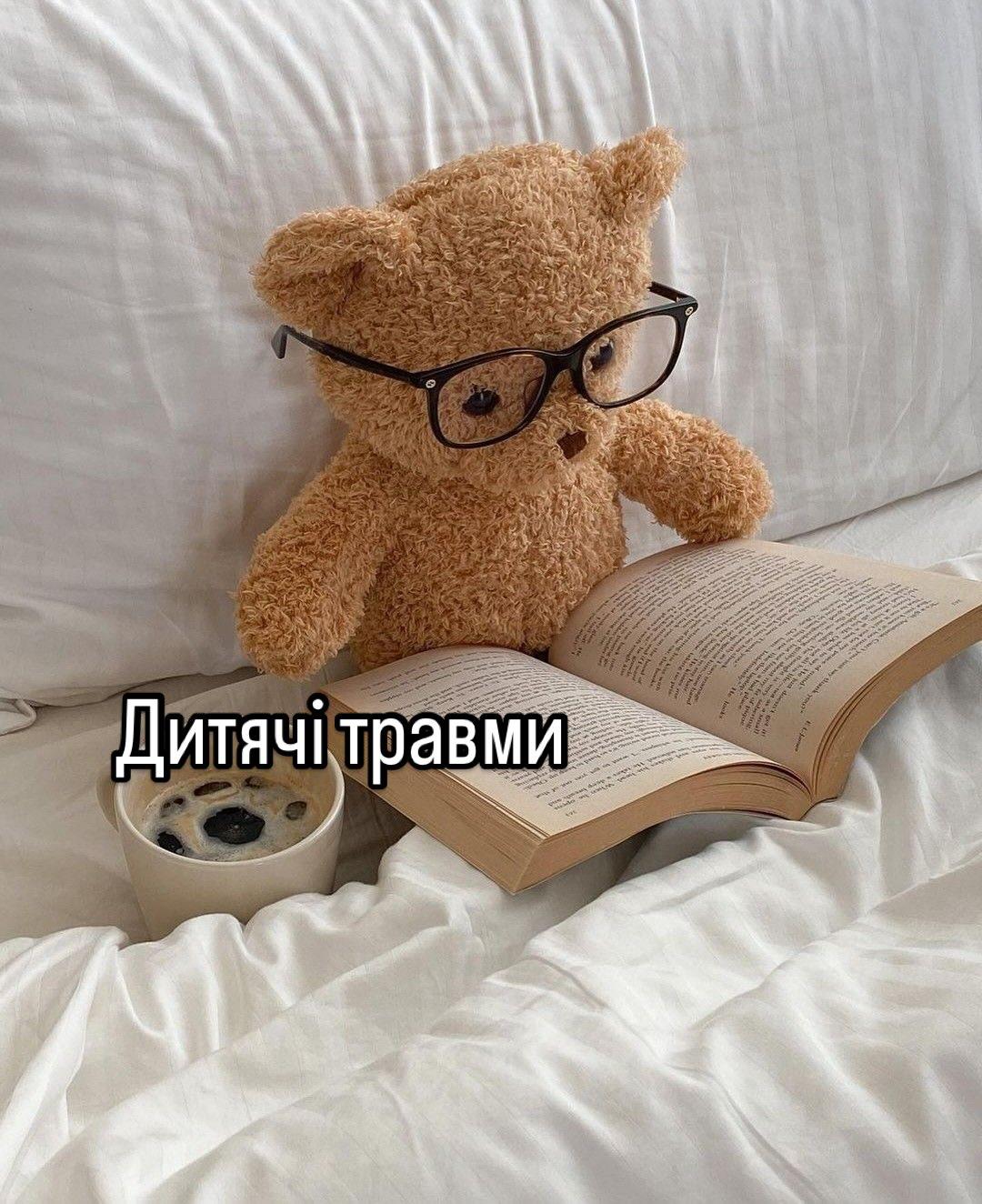 Плюшевий ведмедик в окулярах сидить на ліжку з розгорнутою книжкою; напис «Дитячі травми»