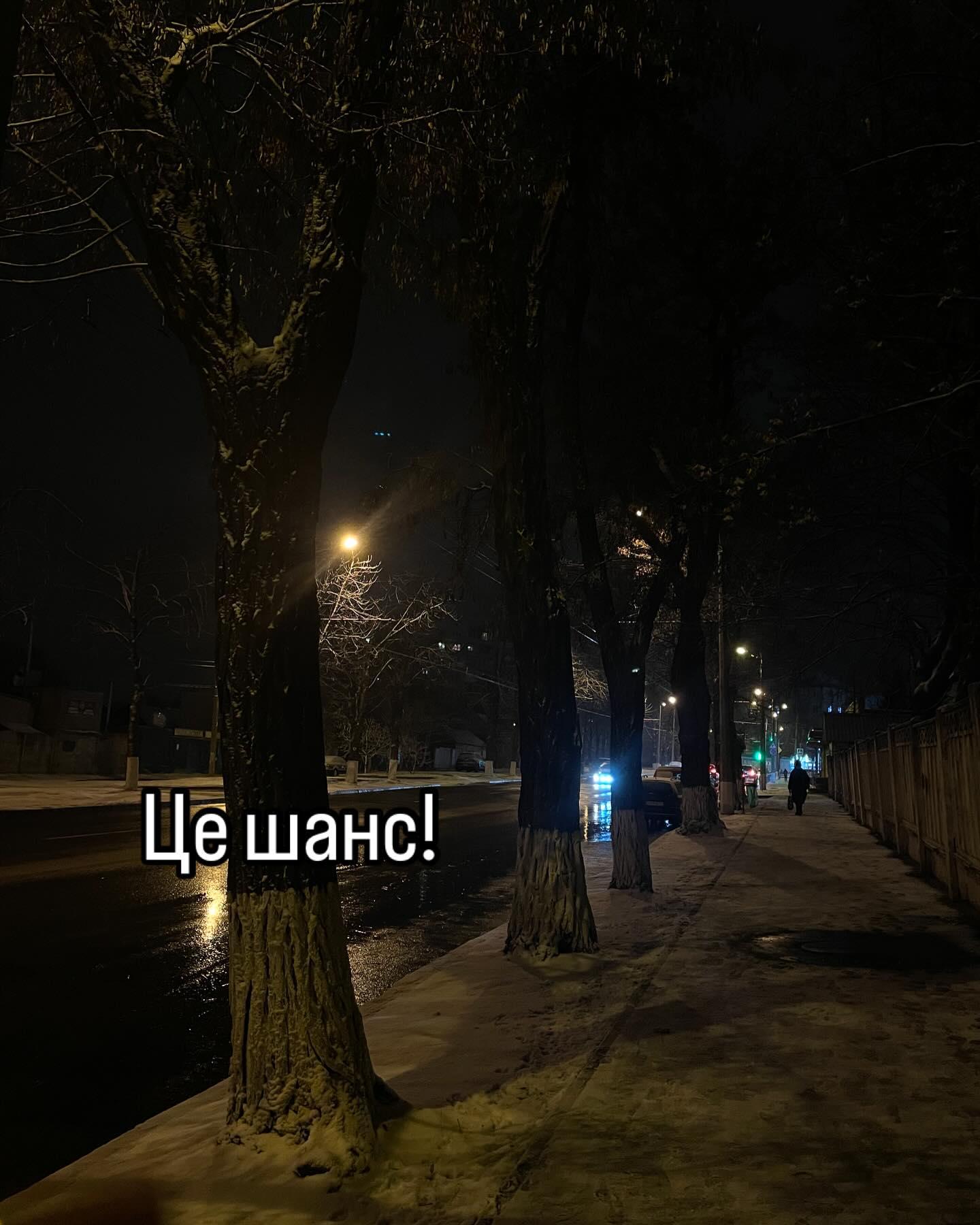 Нічна вулиця з деревами та ліхтарями після дощу; напис «Це шанс!»